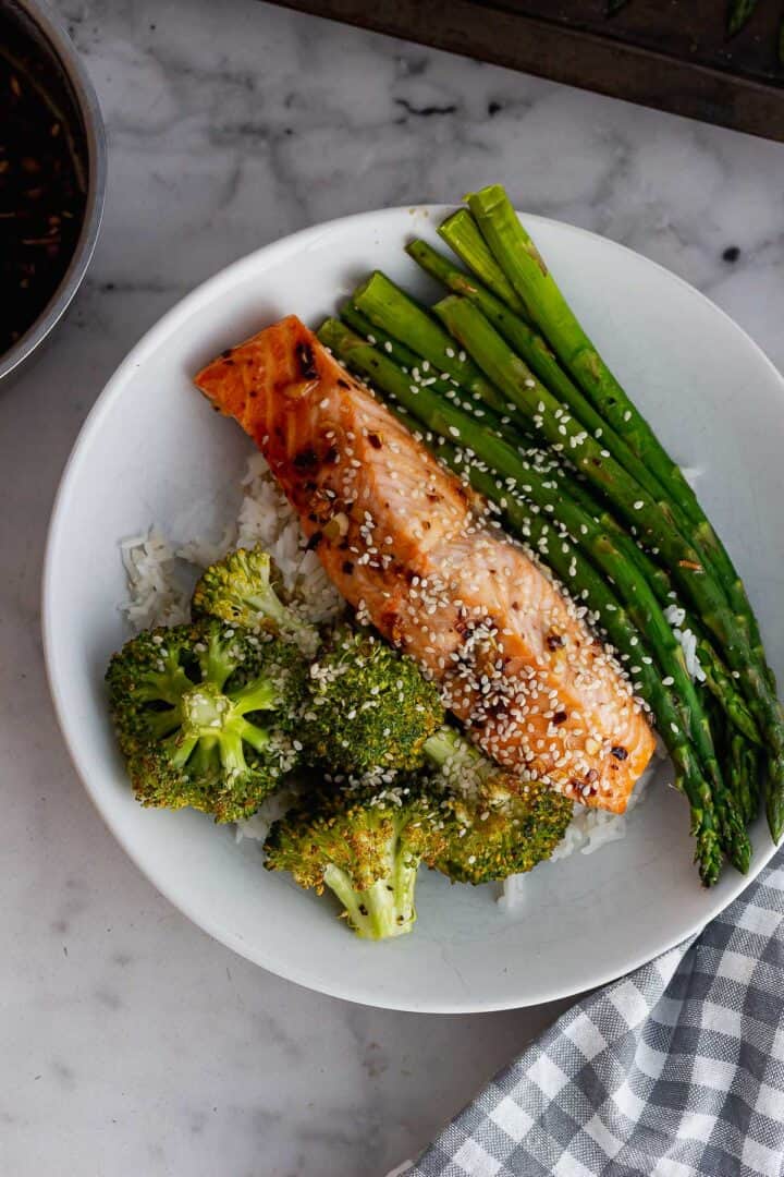 Overhead shot of salmon and vegetable bowls on a marble background