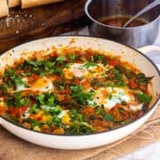 White pan of spinach and eggs on a marble surface