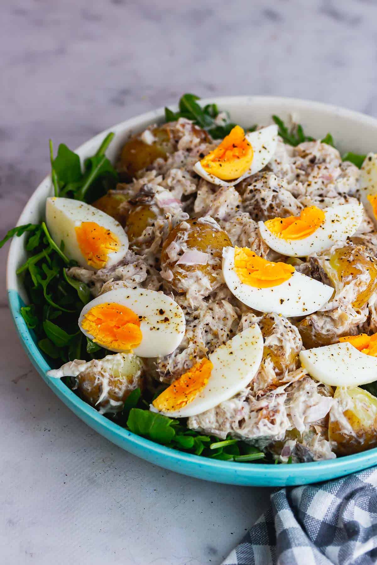 Bowl of potato salad with mackerel topped with boiled eggs