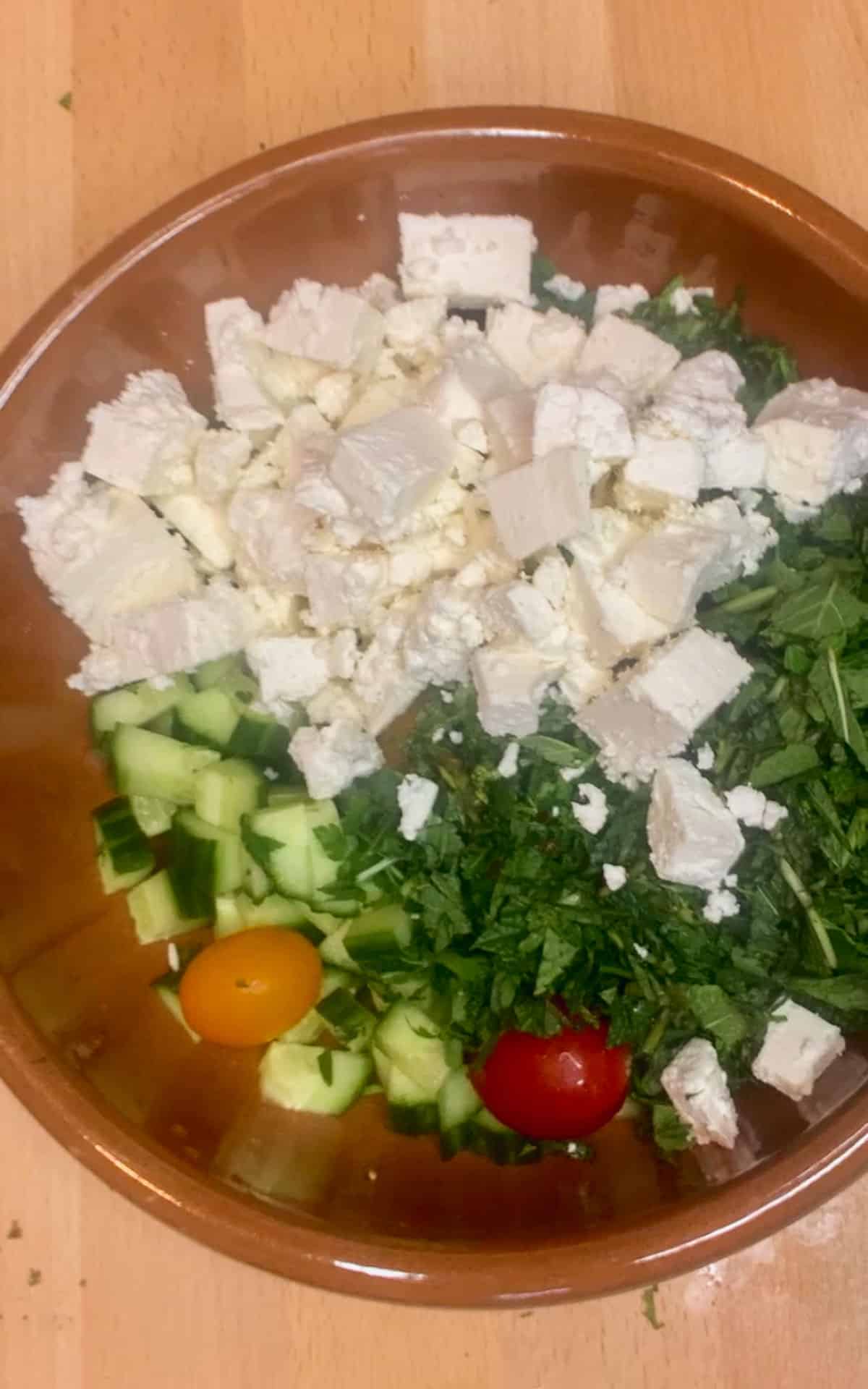Overhead shot of feta and vegetable in a brown bowl