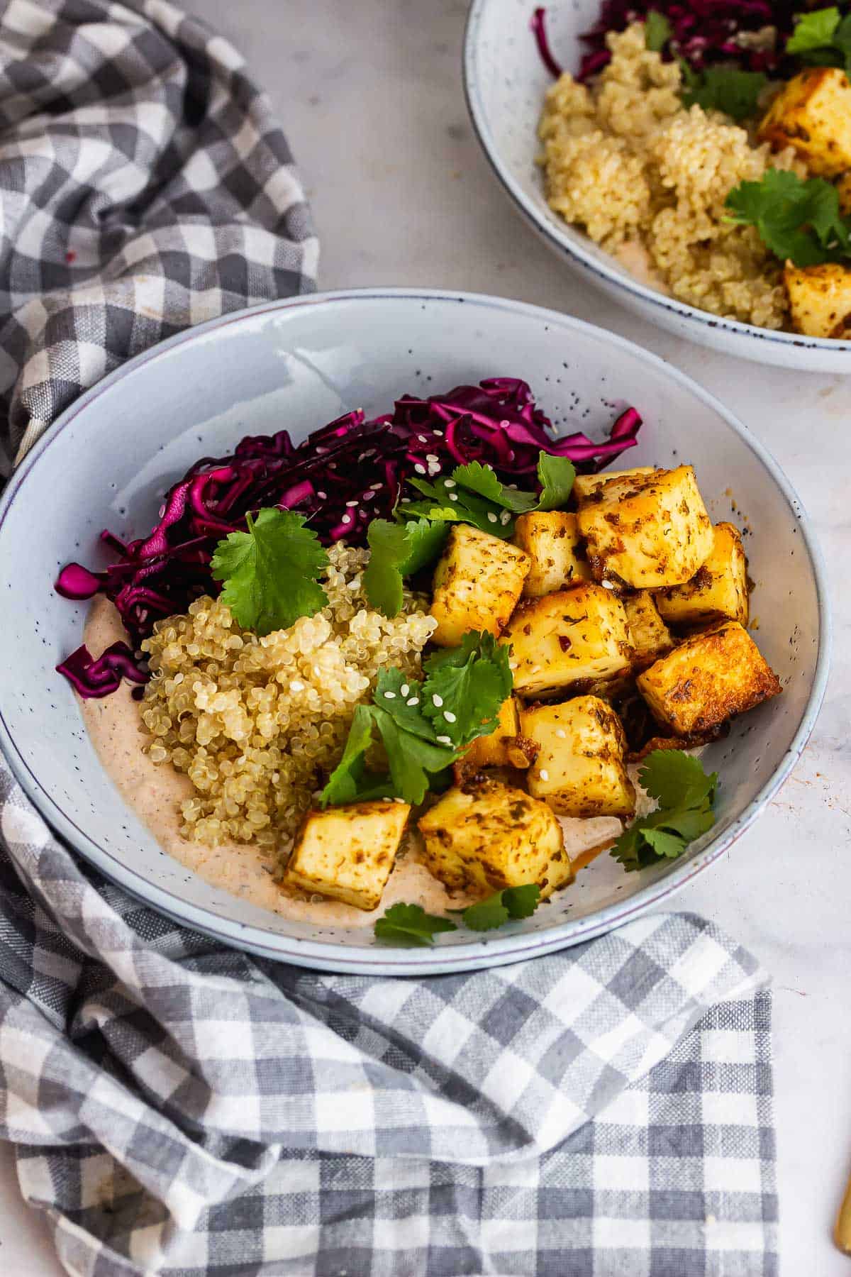 Blue bowl of paneer and quinoa on a checked cloth