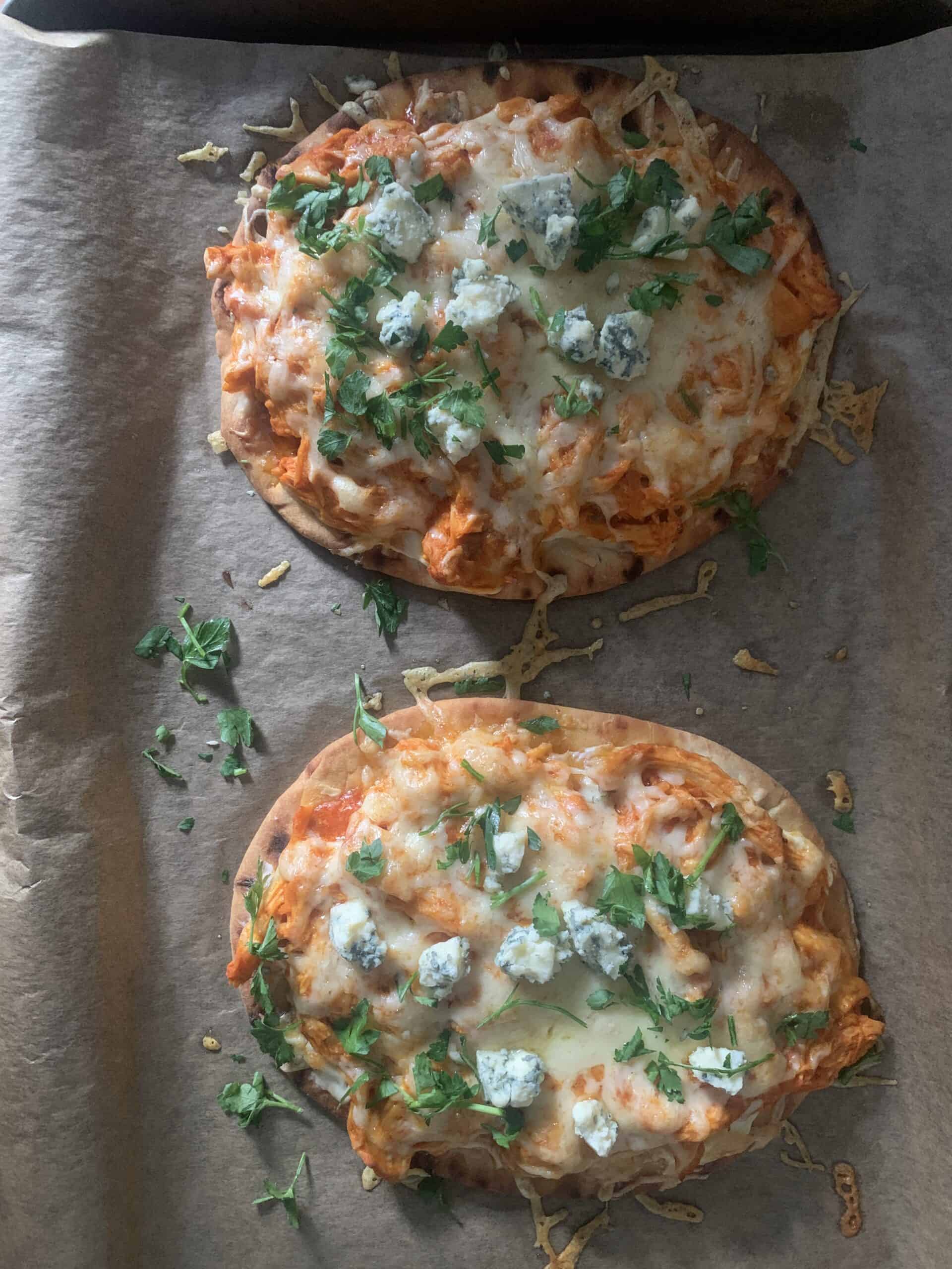 Photo of two buffalo chicken flatbreads topped with blue cheese and herbs