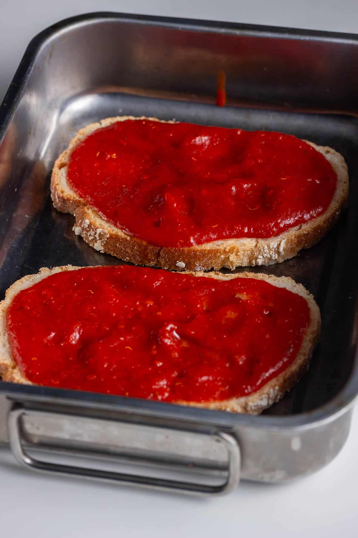 Silver baking tray of toast topped with sauce