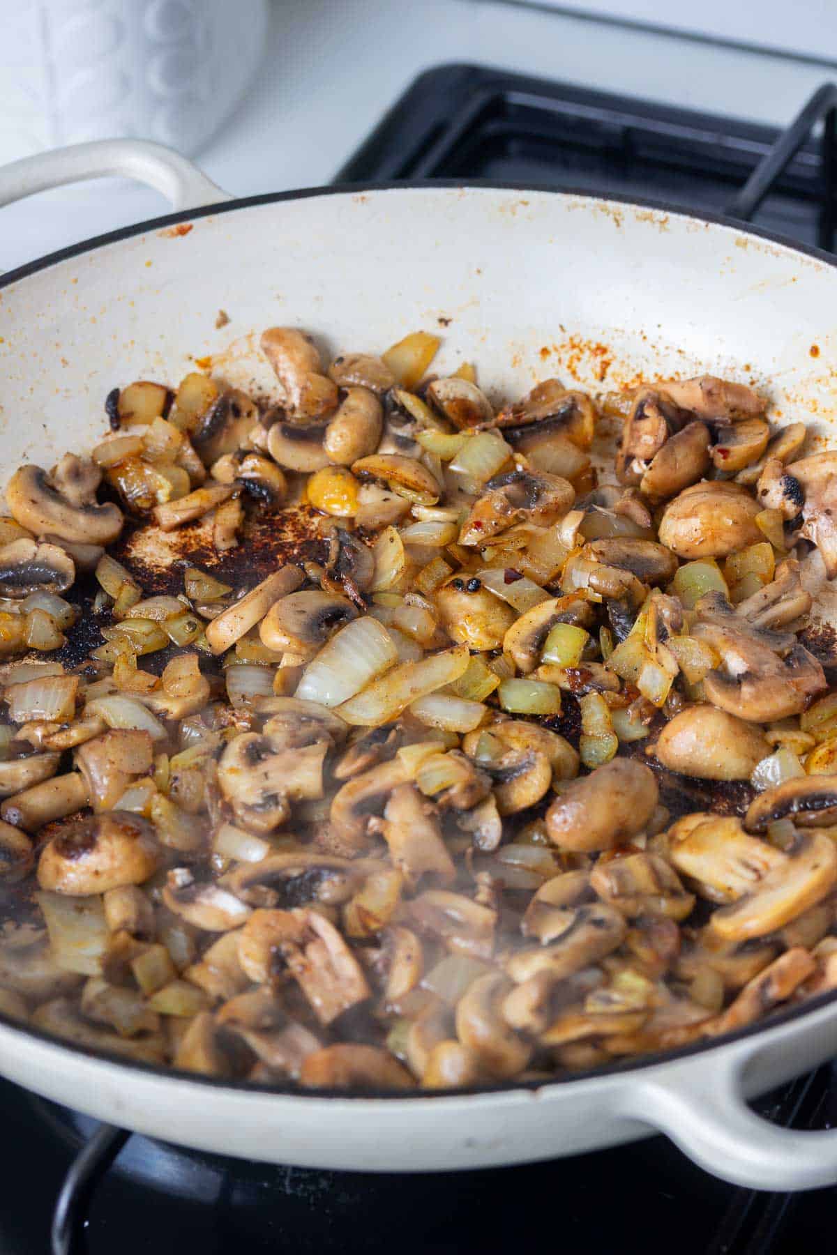 Mushrooms and onion in a white pan