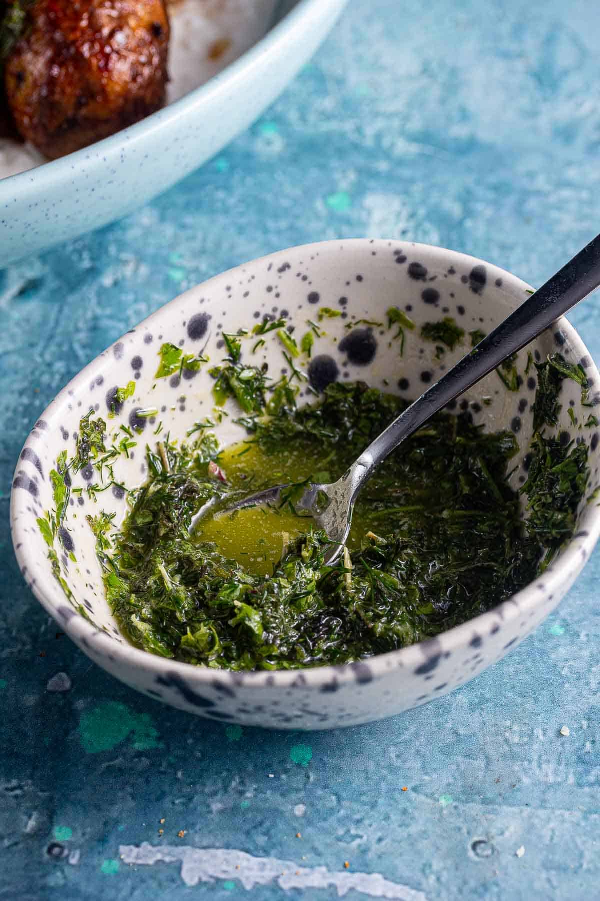 Small spotty bowl of herb oil with a spoon