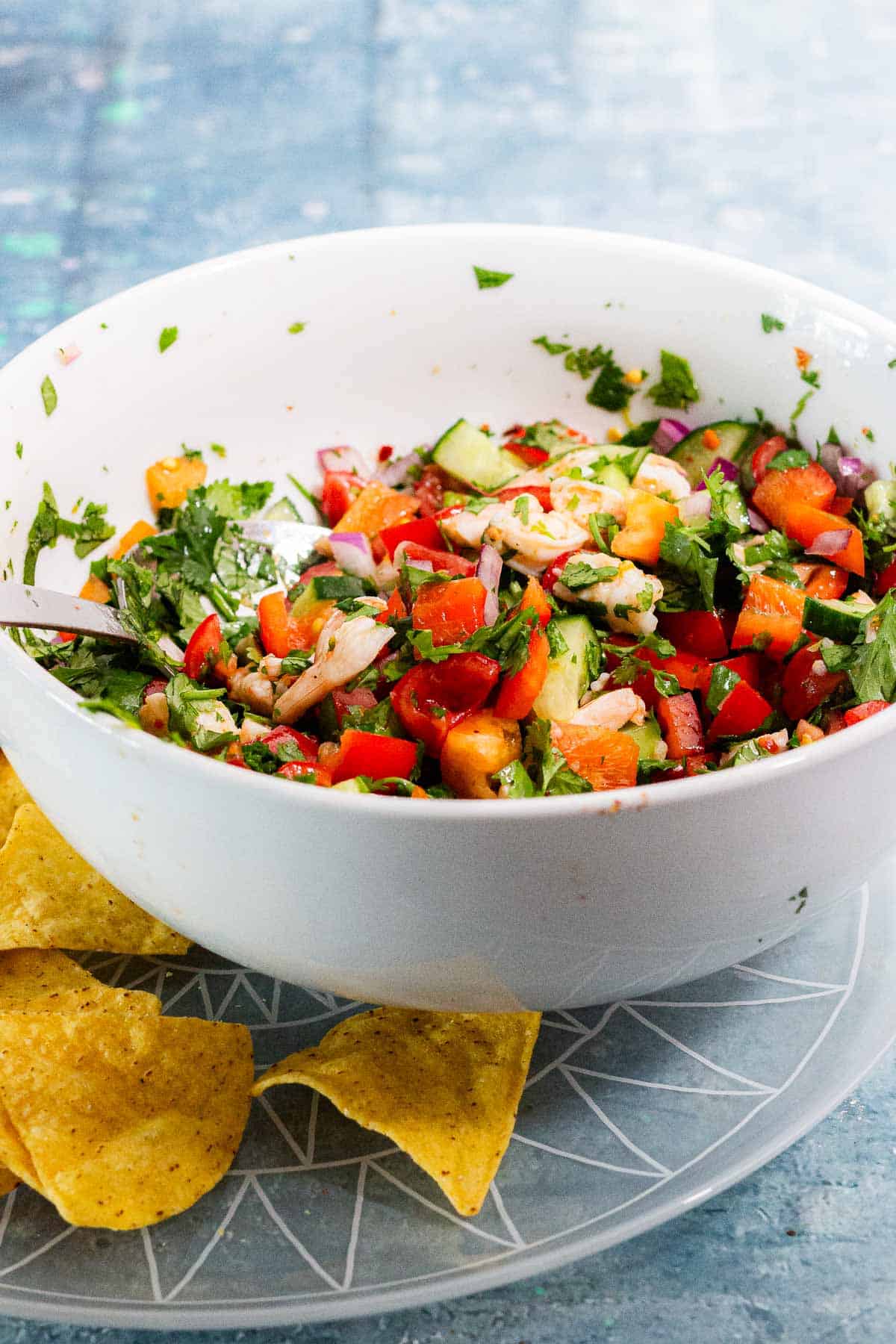 White bowl of prawn salad on a glass platter