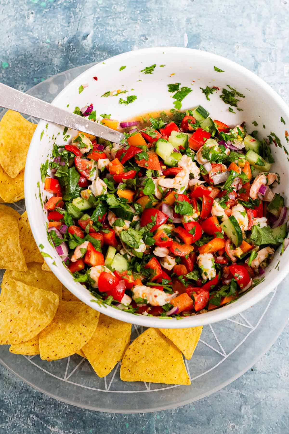 White bowl of salad with tortilla chips on a blue background