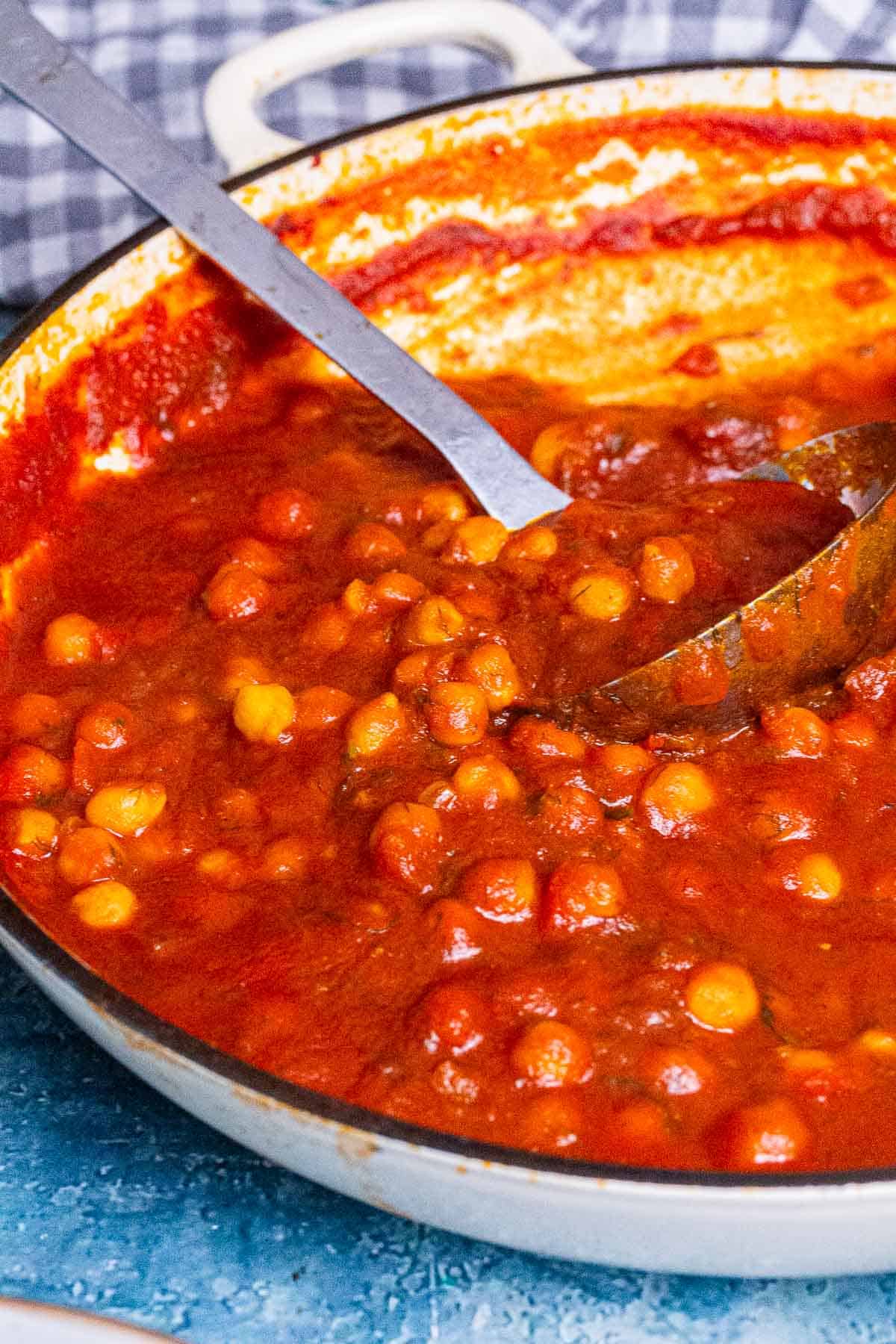 Pot of chickpeas with a ladle on a blue background